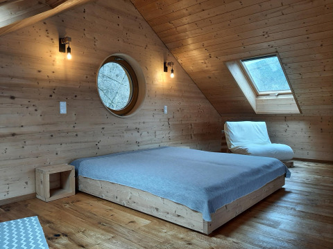 Houten slaapkamer in de Sankt Martin boomhut, laag bed en dakraam, ideale glamping in Rijnland-Palts.