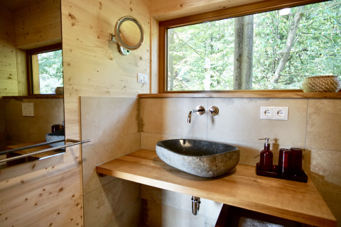 Modern bathroom with stone sink in Sankt Martin boomhut glamping, Boomhutten Rheinland-Palatinate, forest view.