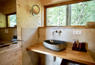 Salle de bain moderne avec lavabo en pierre dans le glamping Sankt Martin boomhut, Boomhutten Rhénanie-Palatinat, vue forêt.