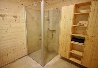 Bagno moderno con doccia in vetro e armadio in legno nel glamping Sankt Martin boomhut.