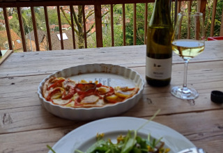 Vue terrasse avec salade, tarte et vin blanc sur table rustique, au Sankt Martin boomhut.
