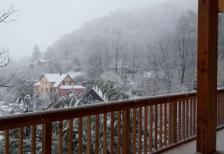 Blick von einer Holzterrasse auf verschneite Bäume und Häuser in der Nähe von Sankt Martin Boomhut, Rheinland-Pfalz.