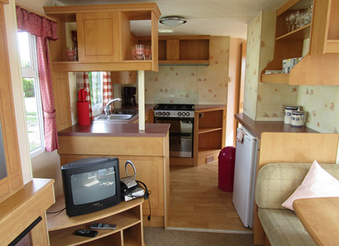 Vista interior de una caravana totalmente equipada en 'Camping Am Leuchtturm' con cocina y sala de estar.