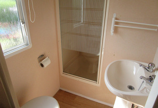Bagno compatto con WC, lavandino, doccia e finestra in una casa mobile glamping in Bassa Sassonia, Germania.
