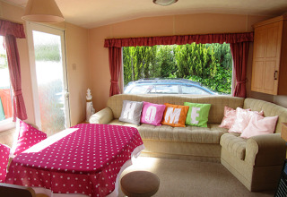 Gemütlicher Innenraum eines Glamping-Stellplatzes mit bunten Kissen, Sofa und großem Fenster.