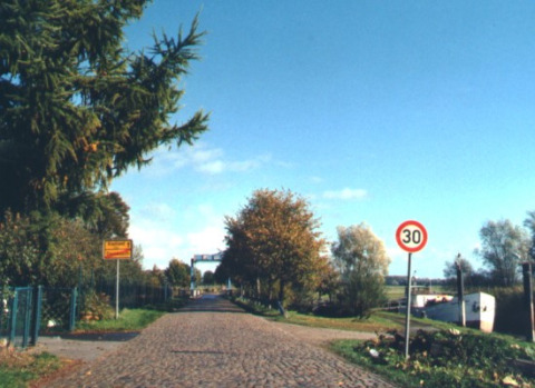 Entrada a Camping 'Am Leuchtturm' - Stacaravans Nedersaksen con señal de velocidad y árboles alrededor.