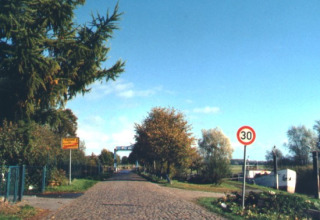 Indgang til Camping 'Am Leuchtturm' - Stacaravans Nedersaksen med vejskilt og træer i baggrunden.