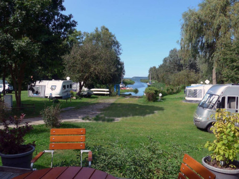 Zicht op Natuurcamping Lassan - Wijnvaten Mecklenburg-Vorpommern met caravans en groenzones langs een rivier.