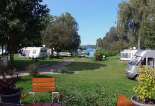 Zicht op Natuurcamping Lassan - Wijnvaten Mecklenburg-Vorpommern met caravans en groenzones langs een rivier.