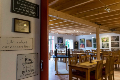 Sfeervolle eetruimte met houten tafels en inspirerende muurteksten bij Natuurcamping Lassan.