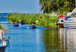 Persone in kayak su un canale vicino a Natuurcamping Lassan, barche e canneti in Mecklenburg-Vorpommern.