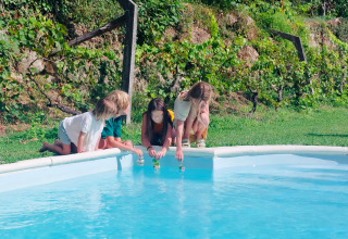 Kinder spielen am Pool im Land of Deveza - Glamping Portugal, umgeben von viel grüner Natur.