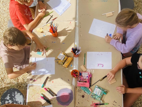 Bambini che fanno lavoretti a un tavolo al Land of Deveza Glamping Portugal, atmosfera da campeggio.