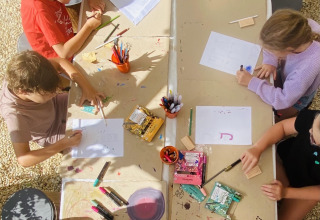Des enfants font des activités manuelles à une table au Land of Deveza Glamping Portugal, ambiance camping.