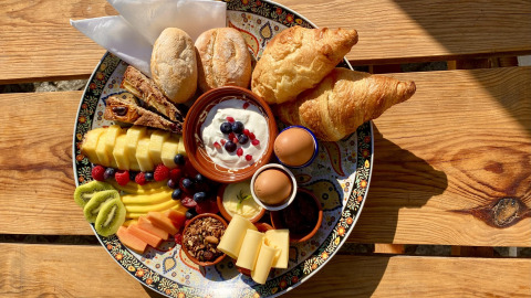 Farverig morgenmadstallerken med frugt, brød, croissanter og yoghurt på Land of Deveza Glamping i Portugal.