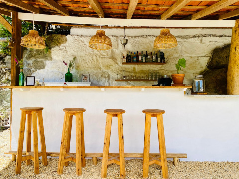 Bar all'aperto a Land of Deveza - Glamping Portugal, con sgabelli in legno e luci a sospensione in vimini.
