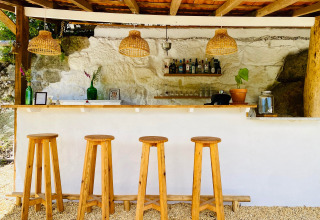 Gemütliche Bar im Freien bei Land of Deveza - Glamping Portugal mit Holzhockern und rustikalem Stil.