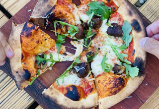 Pizza cotta a legna con funghi e rucola al Land of Deveza - Glamping Portugal, esperienza all'aperto.