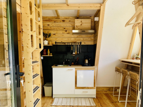 Hébergement glamping moderne à Land of Deveza au Portugal avec intérieur en bois chaleureux et coin cuisine équipé.