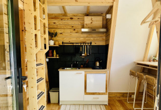 Hébergement glamping moderne à Land of Deveza au Portugal avec intérieur en bois chaleureux et coin cuisine équipé.