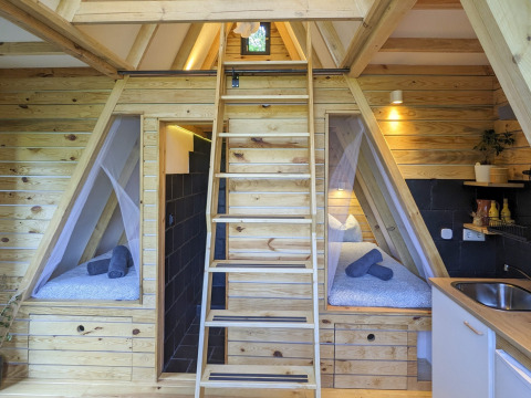 Vista interior de Land of Deveza - Glamping Portugal, con decoración de madera y acogedoras camas individuales.