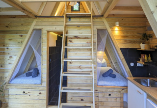 Indvendigt blik på Land of Deveza - Glamping Portugal, med hyggelige træ-interiører og små senge.