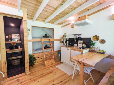 Modern glamping accommodation at Land of Deveza, Portugal, featuring wood interior, kitchen, and cozy beds.