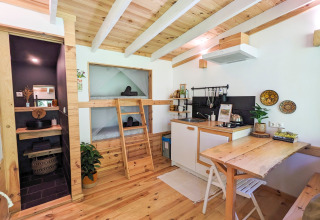 Modern glamping accommodation at Land of Deveza, Portugal, featuring wood interior, kitchen, and cozy beds.