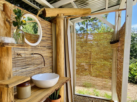 Rustikales Outdoor-Badezimmer mit Holz, Bambus, Waschbecken und Spiegel bei Land of Deveza Glamping Portugal.