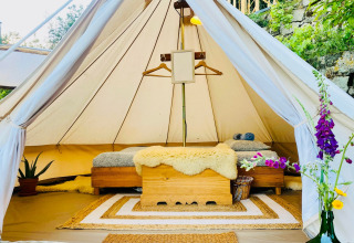 Binnenaanzicht van een sfeervolle glamping tent met bedden en decoratie bij Land of Deveza Glamping Portugal.