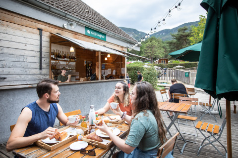 Trois personnes prennent le petit-déjeuner en terrasse au Huttopia Divonne Les Bains - Glamping Rhône-Alpes.