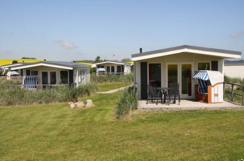 Drie moderne glampinglodges op Camping Walkyria aan de Oostzee, met terras en omgeven door groen gras.