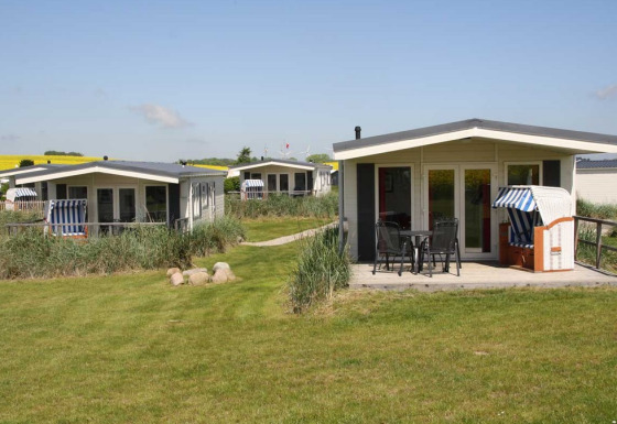 Three modern glamping lodges at Camping Walkyria by the Baltic Sea, with outdoor seating and greenery.