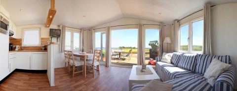 Heldere glampinglodge bij Camping Walkyria met keuken, eethoek en uitzicht op de Oostzee vanaf het terras.