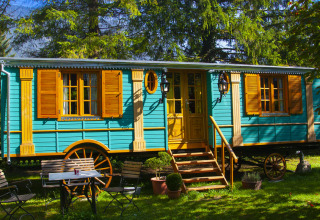 Kleurrijke glampingwagen bij Park am See vakantiewoning in Obertraun, Oostenrijk, omgeven door bomen.