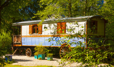 Glampingindkvartering i Park am See, Obertraun, Østrig: charmerende farverig vogn i frodig natur.