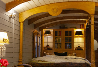 Cozy glamping accommodation with wooden interior, double bed, and warm lighting at Park am See, Austria.