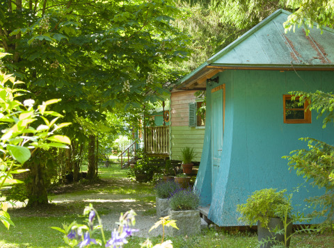 Glamping accommodation with colorful cabins surrounded by greenery at Park am See, Obertraun, Austria.
