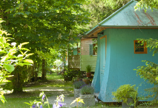 Glamping accommodation with colorful cabins surrounded by greenery at Park am See, Obertraun, Austria.