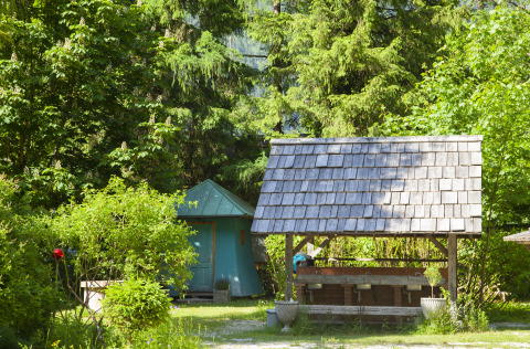 Glamping accommodation Park am See in Obertraun, Austria, surrounded by lush green trees and outdoor sinks.
