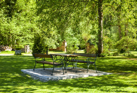 Udendørs siddeområde i en grøn, skyggefuld have ved Park am See glamping i Obertraun, Østrig.