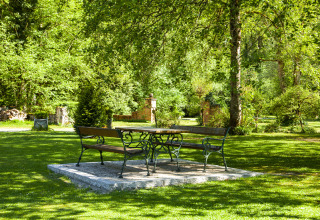 Banken en tafel in een groen park bij Park am See, glamping accommodatie in Obertraun, Oostenrijk.
