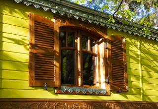 Colorful wooden facade with green walls and open shutters at Park am See glamping in Obertraun, Austria.