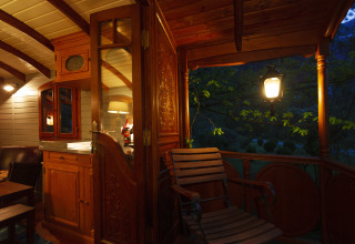 Sfeervolle glampingaccommodatie met houten meubels en verlichte veranda in de avond in Obertraun, Oostenrijk.