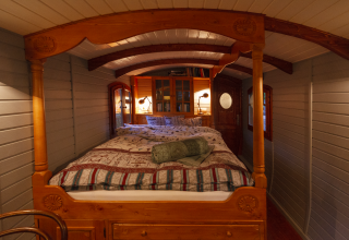 Cozy glamping accommodation at Park am See in Obertraun, Austria, featuring a wooden bed and warm lighting.