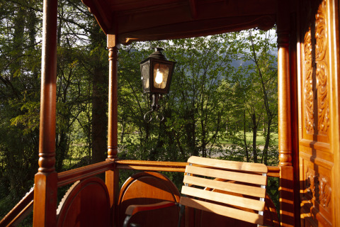Traditionele houten veranda met lantaarn en bosuitzicht, Park am See glamping in Obertraun, Oostenrijk.