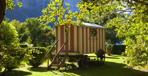 Glamping accommodation: red and yellow striped wagon at Park am See vacation home in Obertraun, Austria.