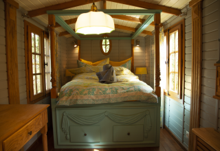 Knusse glampingaccommodatie met hemelbed, houten wanden en ramen in Obertraun, Oostenrijk.