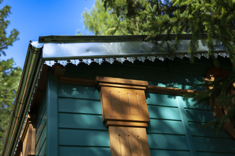 Detail of green wooden glamping cabin with decorative trim at Park am See, Obertraun, Austria, in nature.