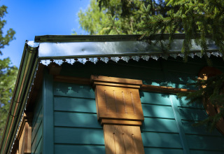 Detail of green wooden glamping cabin with decorative trim at Park am See, Obertraun, Austria, in nature.